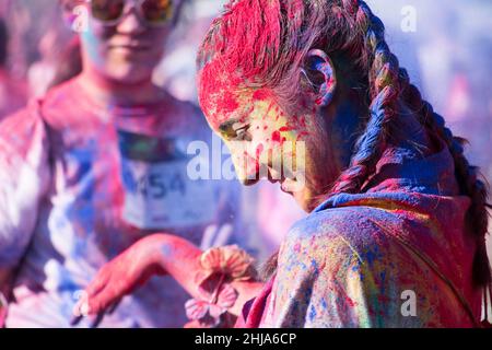 Valencia, Spain - April 27, 2019: Young woman side portrait covered with multi colored powders smiling during the "Holi life" race Stock Photo