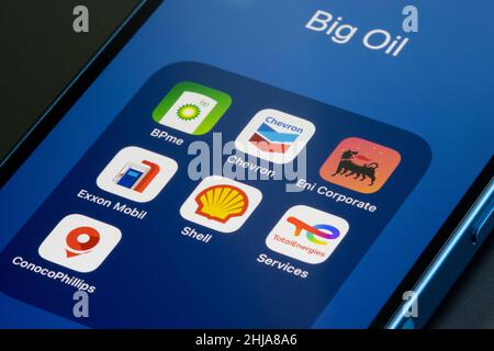 App icons representing Big Oil (supermajors) - BP, Chevron, Eni, ExxonMobil, Royal Dutch Shell, TotalEnergies, ConocoPhillips - are seen on an iPhone. Stock Photo