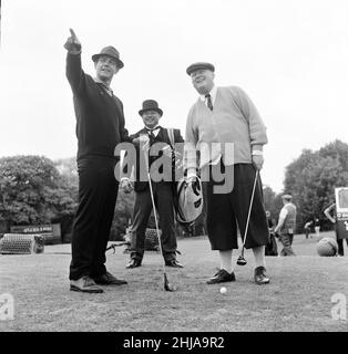 Filming the golf scene for 'Goldfinger' at Stoke Park golf course near Stoke Poges, Buckinghamshire, were Sean Connery ( James Bond ) Gert Frobe ( Goldfinger ) and Harold T Sakata who is better known as ' Tosh Togo ' in the Wrestling World. Harold is playing the part of the caddy for this scene.In the film James Bond and Goldfinger play for a £5000 stake. The game is crooked from the start to finish, but Bond wins in the end of course.  21st May 1964 Stock Photo