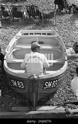 Holiday scenes at Brighton .Lifeguard sitting in a rowing boat on Brighton beach. 7th July 1963 Stock Photo