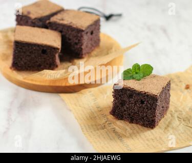 Black Glutinous Rice Chiffon Cake. Soft and Moist Sliced Cake, Made from a Black Sticky Rice Flour or Chiffon Ketan Hitam. Served on White Table. Copy Stock Photo