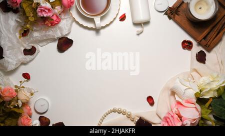 Feminine workspace with copy space, roses bouquet, candles, textiles, and decor on white background. top view, flat lay Stock Photo