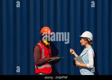 Businesswoman and engineer talking and checking loading Containers box from Cargo freight ship for import export. shipping in docks. Stock Photo