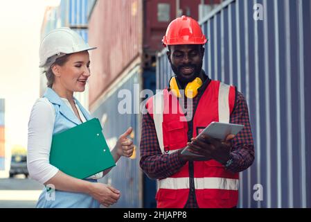 Businesswoman and engineer talking and checking loading Containers box from Cargo freight ship for import export. shipping in docks. Stock Photo