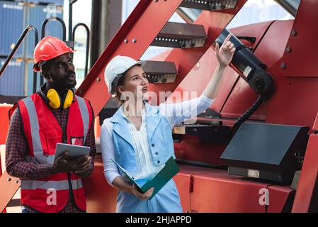 Businesswoman and engineer talking and checking loading Containers box from Cargo freight ship for import export. shipping in docks. Stock Photo
