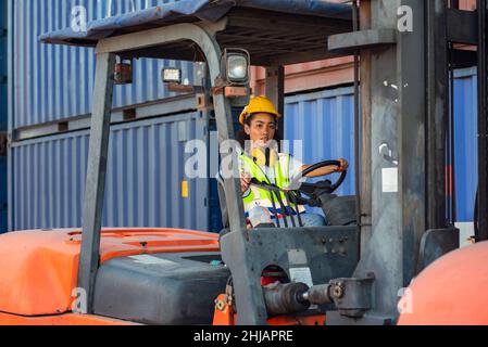 Female foreman is driving forklift at shipping container yard. shipping in docks. Stock Photo