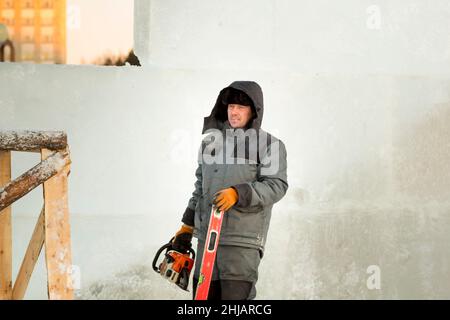 Worker with a chainsaw in hand at the assembly site Stock Photo