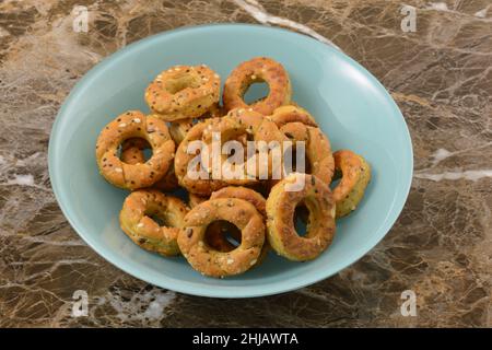 Pretzel cracker rings with topping of sesame seeds, chia, and flax seeds in blue snack bowl Stock Photo