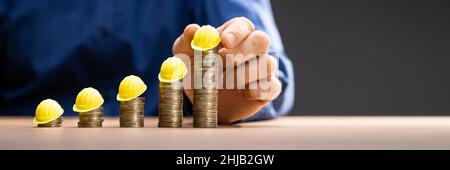Construction Insurance And Budget Inflation. Coin And Hard Hat Stock Photo