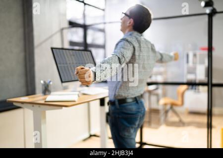 Man Doing Stretch Exercise At Work In Office Stock Photo