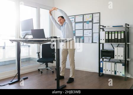 Man Doing Stretch Exercise At Work In Office Stock Photo