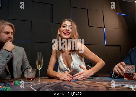 Brown-haired girl enjoying successful poker game raking pile of chips Stock Photo