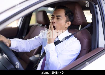 Business man looks tired yawning while driving the car Stock Photo
