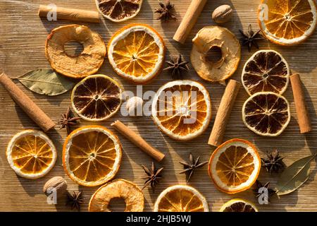 Top view of dry pieces of lemon, orange and apples, cinnamon sticks, bay leaves, nutmegs and star anise as background as ingredients for mulled wine a Stock Photo