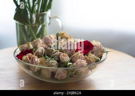 Dry rose buds in glass bowl and stems in glass with water. Concept for handmade Stock Photo