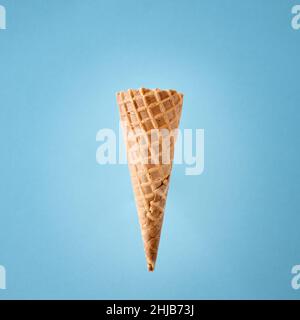 Empty wafer ice cream cone on blue background. Stock Photo