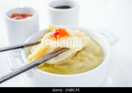 Steamed dumplings and soy sauce. asian dumplings Gyoza potstickers in white ceramic plate served with chopsticks over linen table cloth. Stock Photo
