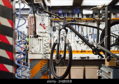 Modern bicycle and different instruments and working tools hanging on wall in retail store with large assortment Stock Photo