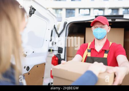 Male courier in face mask give receiver order in cardboard Stock Photo