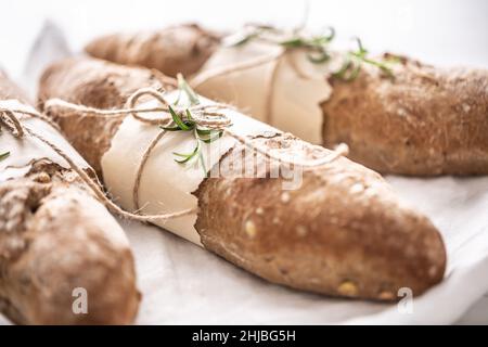 Detail of fresh crusty wholegrain breads on a white surface. Stock Photo