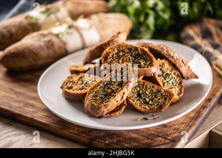 Slices of freshly baked garlic bread with butter piled on a plate in the kitchen. Stock Photo