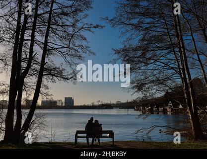 Schwerin, Germany. 28th Jan, 2022. A couple enjoys the sunny winter weather on a bench at the Ziegelsee in Schwerin. Credit: Ulrich Perrey/dpa/Alamy Live News