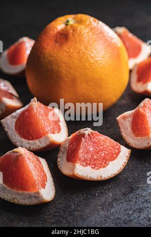 Sliced citrus fruit. Chopped fresh grapefruit on a black table. Stock Photo