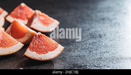 Sliced citrus fruit. Chopped fresh grapefruit on a black table. Stock Photo