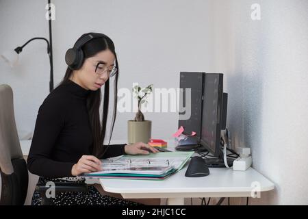 Serious asian business woman analyzing indexes and financial charts. Stock Photo