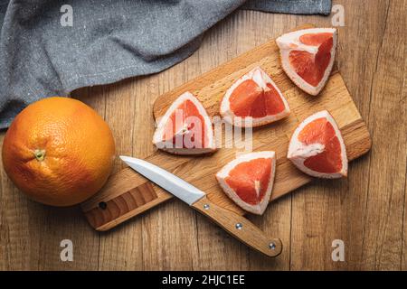 Sliced citrus fruit. Chopped fresh grapefruit on a cutting board. Top view. Stock Photo