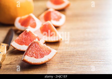 Sliced citrus fruit. Chopped fresh grapefruit on a wooden table. Stock Photo