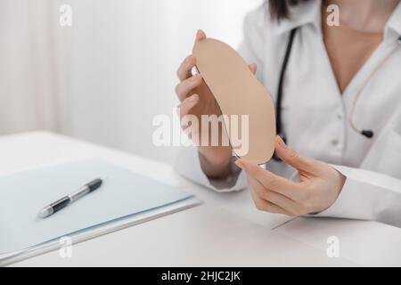 Doctor holding an insole while sitting at a table. Orthopedist tests the medical device. Orthopedic insoles. Foot care. Flat Feet Correction Stock Photo