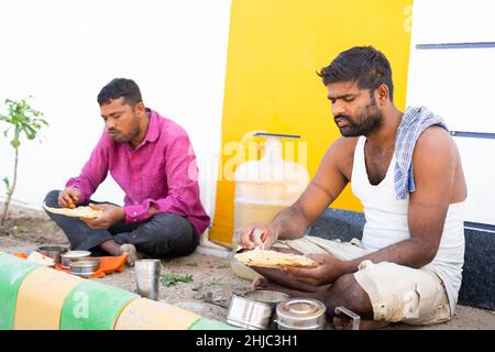 Indian construction worker busy having afternoon lunch at workplace - concept of hygiene, healthcare, break time and daily wagers lifestyle Stock Photo