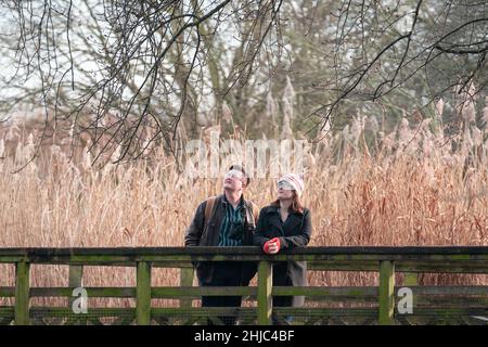 Alistair Hyde (left) and Sarah Christie look for birds whilst walking at the WWT (Wildfowl and Wetlands Trust) London Wetland Centre in Barnes, west London ahead of this weekend's RSPB Big Garden Birdwatch. The annual survey encourages people to watch the birds in their garden or local park for an hour over the weekend and record the greatest number of each species they see. Picture date: Friday January 28, 2022. Stock Photo