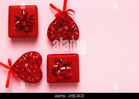 Red Valentine hearts and gift boxes on a pink background with copy space. Stock Photo