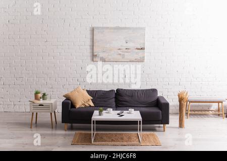 Cups of coffee near smartphone and remote controller on coffee table in living room Stock Photo