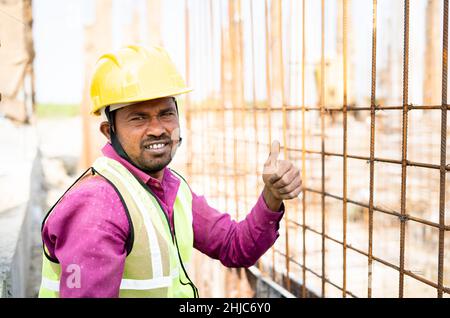 Construction worker with hardhat and jacket showing thumbs-up while working by looking at camera - concept of hard-working, successful and job Stock Photo