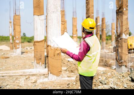 young indian engineer or supervioser inspecting construction plan at workplace - concept of skilled labour,daily wager lifestyle and construcation Stock Photo