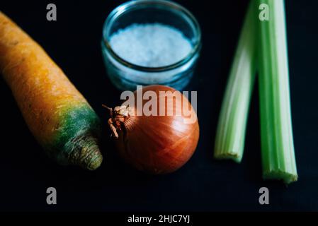 Celery, carrot and onion on slate with salt on slate. Traditional ingredients for the french culinary base mirepoix, or Italian Soffritto Stock Photo