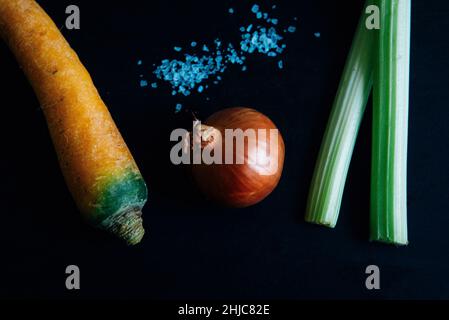 Celery, carrot and onion on slate with salt on slate. Traditional ingredients for the french culinary base mirepoix, or Italian Soffritto Stock Photo