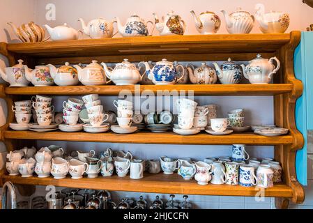 Assortment of hand painted ceramic floral pattern tea sets on shelves Stock Photo