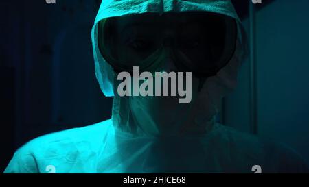 Man in medical protective suit and masks in dark. Stock footage. Mannequin in protective suit against coronavirus or radiation. Flashing light over ma Stock Photo