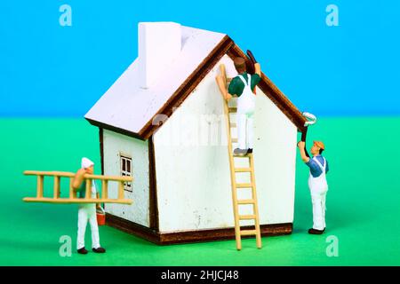Conceptual image of miniature figure decorators painting the walls of a model house Stock Photo