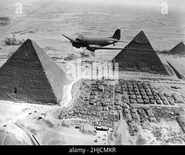 A U.S. Army Air Forces Air Transport Command Douglas C-47 Skytrain flying over the Giza pyramids in Egypt, during World War II, 1943. Loaded with urgent war supplies and materials, this plane was one of a fleet flying shipments from the U.S. across the Atlantic and Africa to strategic battle zones. Stock Photo