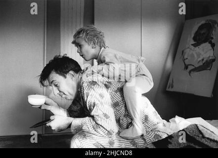 A black and white photograph taken of a boy climbing on his father in the early morning. Photograph taken for the Ladies' Home Journal circa 1963. Stock Photo