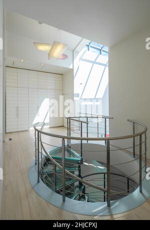 A spiral staircase hall with wardrobe and white walls and doors lead to ...