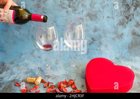 Woman pouring glass of red wine from a bottle. Closeup of a preparation for a special Valentine's Day celebration evening. Stock Photo
