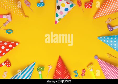 Colored party hat and candles lying on yellow background. Birthday, holiday concept. Stock Photo