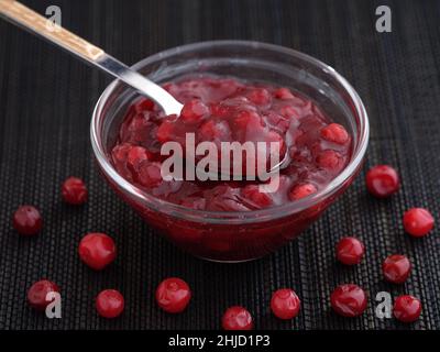 Homemade wild lingonberry jam in a glass bowl. Low key. Close up. Stock Photo