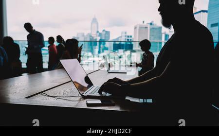Faceless man typing on laptop in open space office Stock Photo